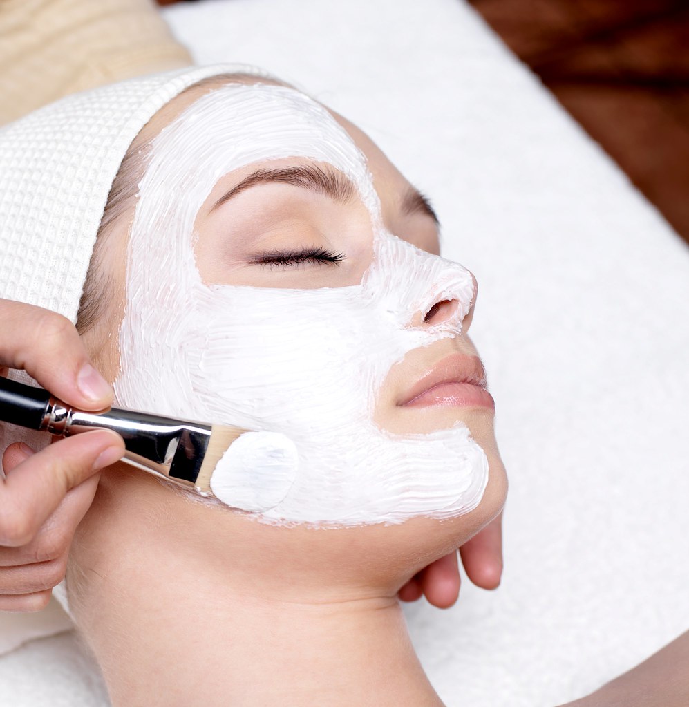 Esthetician applying a facial mask during a professional skin care treatment